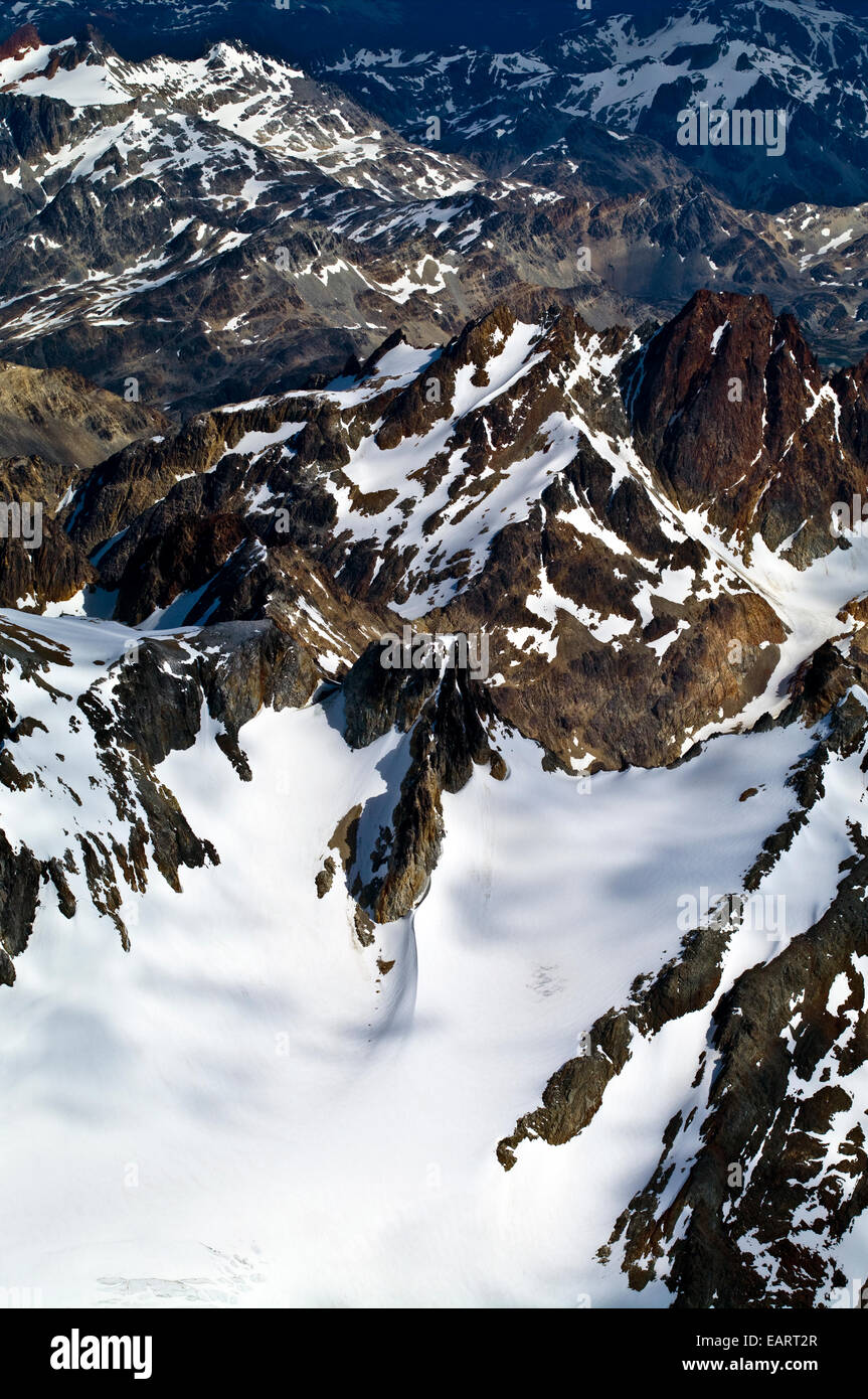 Correctifs de nuages gris et de la lumière du soleil sur les sommets de montagne enneigée déchiquetées. Banque D'Images