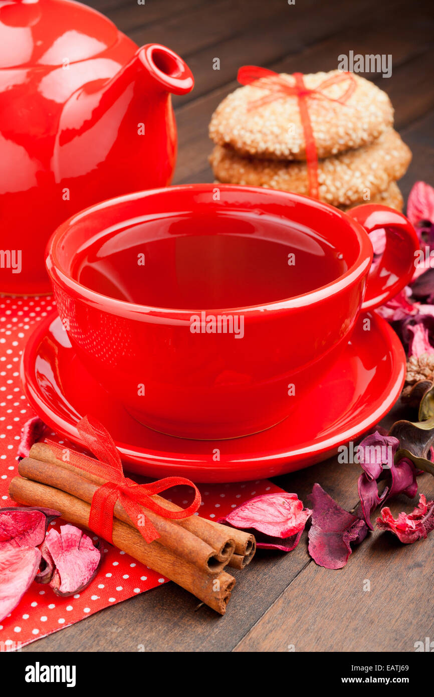 Maison de vacances plateau en rouge tasse, théière, cookies et des bâtons de cannelle sur table de cuisine Banque D'Images