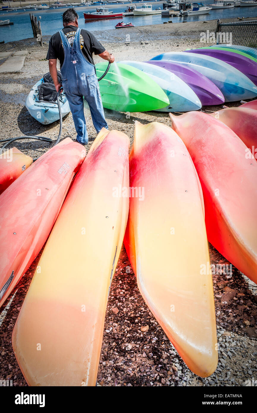 Cet homme passe la plupart de son temps à apporter de l'eau les bateaux, lave le sel de toutes les location de kayaks,pour les faire durer plus longtemps. . Banque D'Images