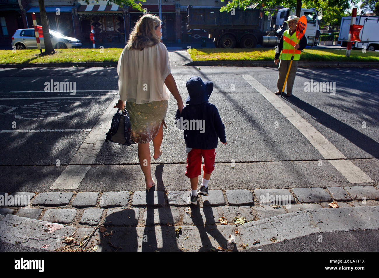 Une mère traverse une route très fréquentée avec son fils sur son premier jour d'école. Banque D'Images Une mère traverse une route très fréquentée avec son fils sur son premier jour d'école. Banque D'Images