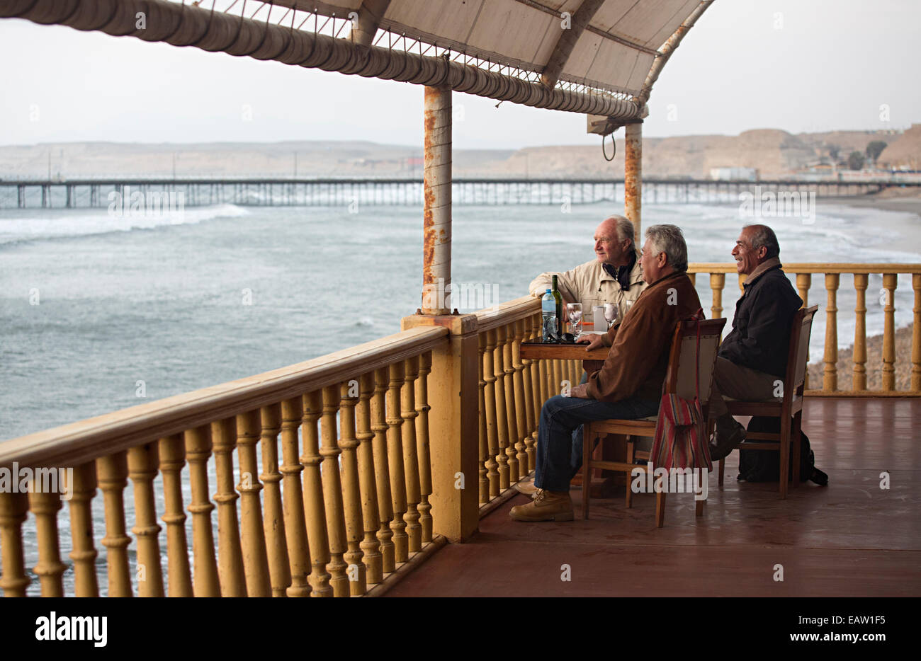 Trois amis prendre un verre et une bonne conversation avec le style colonial balcon donnant sur l'océan à Pacasmayo La Libertad Banque D'Images