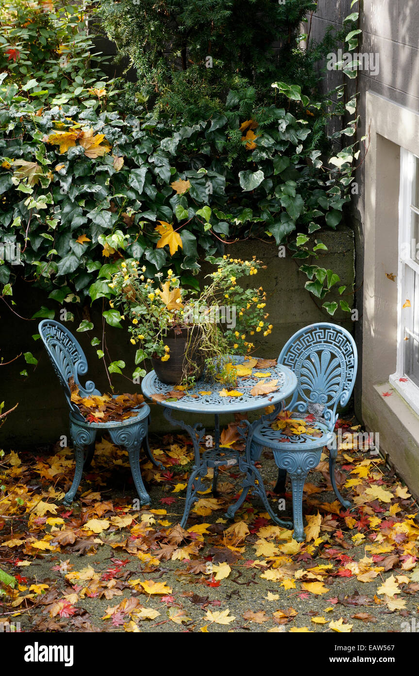 Fer forgé bleu table et chaises sur un patio couvert de feuilles d'automne Banque D'Images