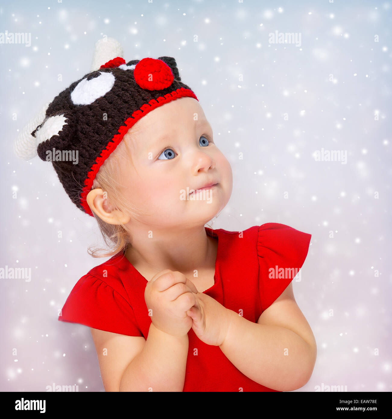 Cute little girl portrait, sweet baby wearing Rudolf hat isolé sur fond de neige gris, concept célébration de Noël Banque D'Images