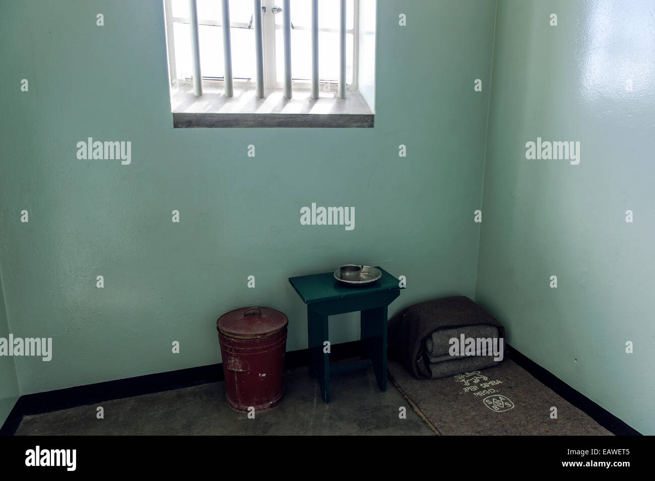 Une tasse, bol et lit de camp dans la cellule habitée par Nelson Mandela. Banque D'Images