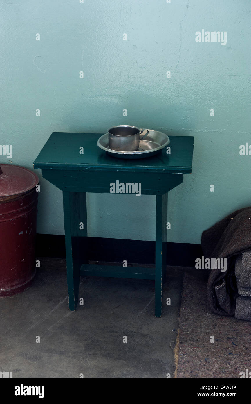 Une table contient une tasse et un bol dans la cellule habitée par Nelson Mandela. Banque D'Images
