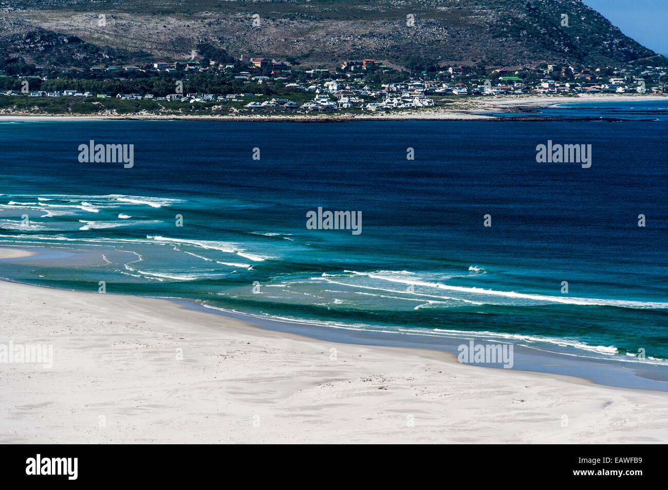 Les vagues roulent sur une plage de sable blanc entourée d'une baie ...