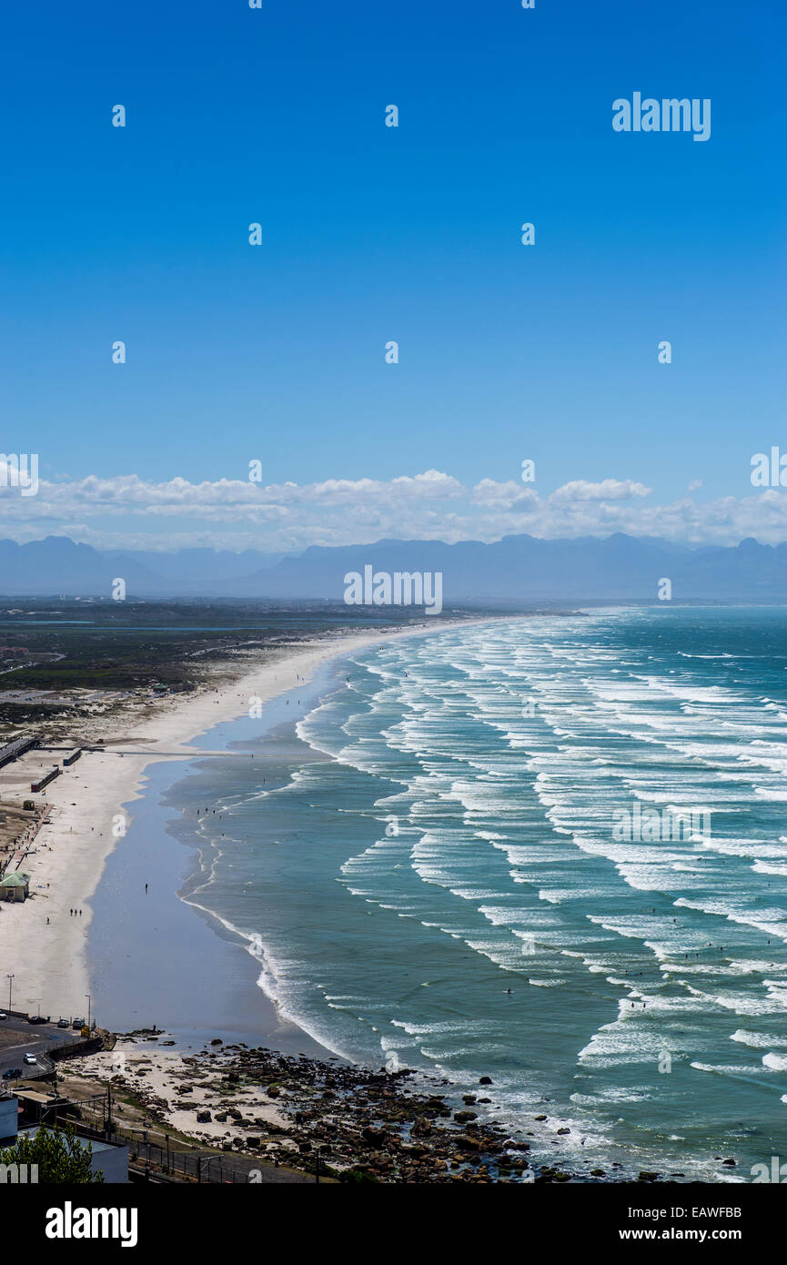 Les vagues sans fin rouleau sur une longue plage de sable blanc sous un ciel d'été. Banque D'Images