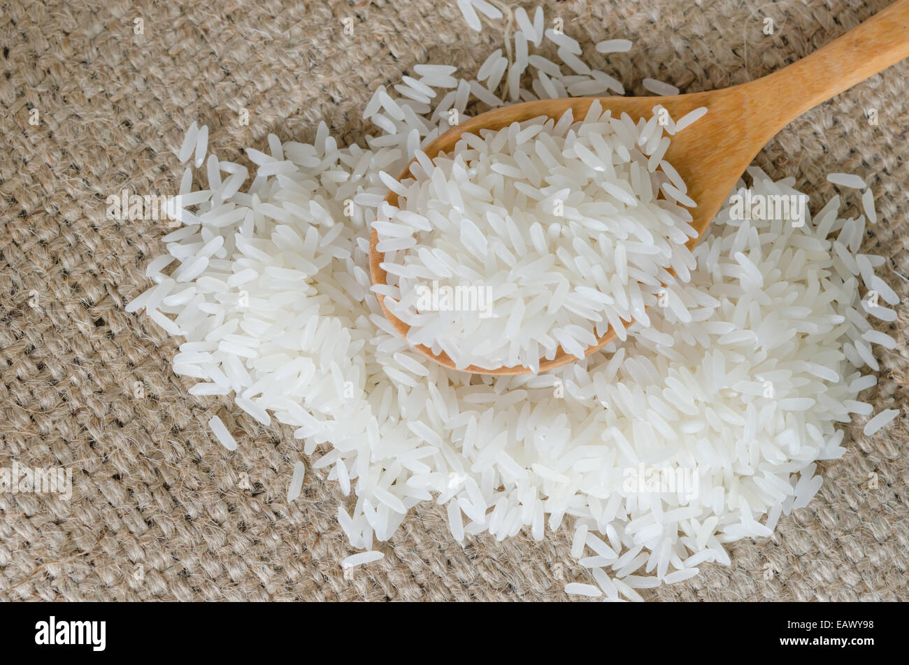Les grains de riz blanc avec cuillère en bois sur le sac Banque D'Images