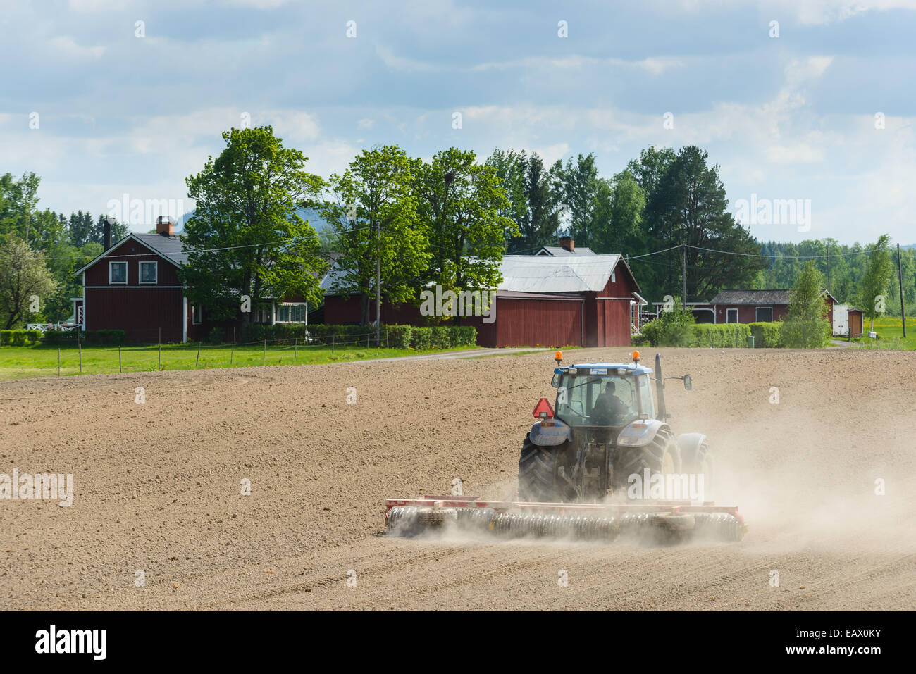 Fermier dans un tracteur laboure un champ Banque D'Images