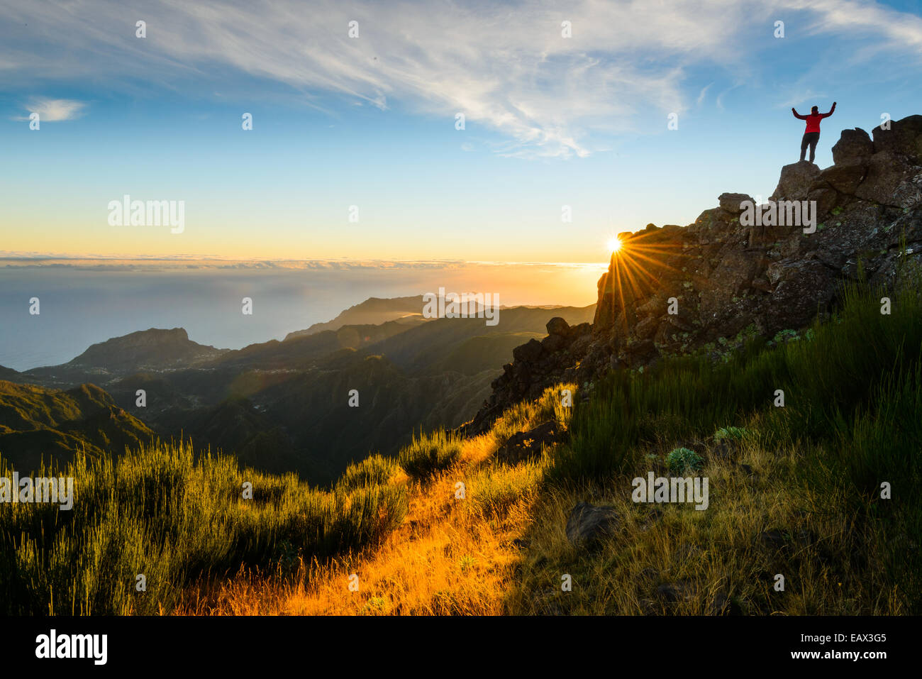 Randonneur avec bras levés au sommet d'une montagne au lever du soleil, Pico do Arieiro, Madère Banque D'Images