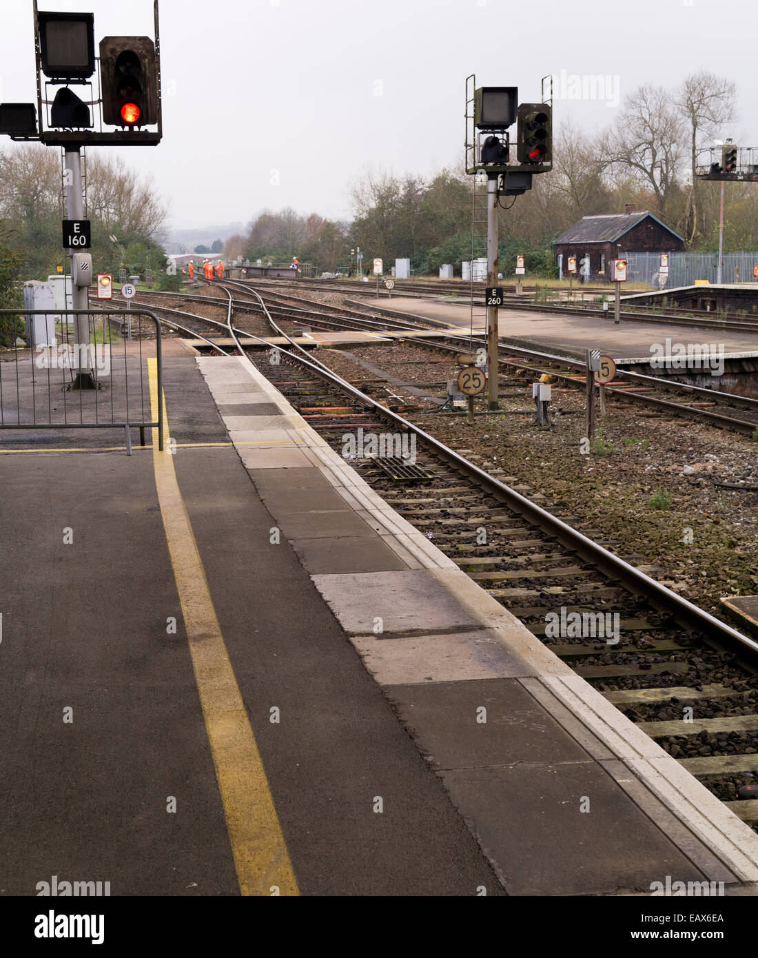 Lumière rouge à gare comme l'entretien des chemins de travailleurs dans des vêtements haute visibilité effectuer les travaux en voie. Banque D'Images