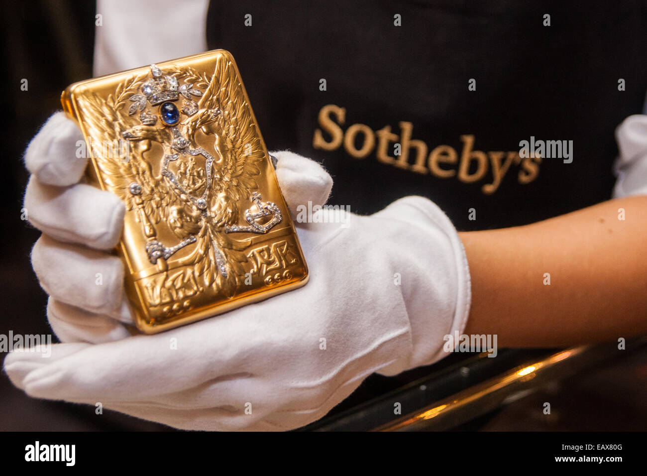 Sotheby's, Londres, 21 novembre 2014. Sotheby's présente l'un de ses plus forts des offrandes de Fédération de peintures, icônes et les œuvres que la célèbre maison de vente aux enchères d'art fête ses 25 ans en Russie. Photo : Sotheby's un technicien galerie affiche une présentation de l'or impérial jeweled cigarette cas par Faberge, doué par l'Empereur Nicolas II. Crédit : Paul Davey/Alamy Live News Banque D'Images