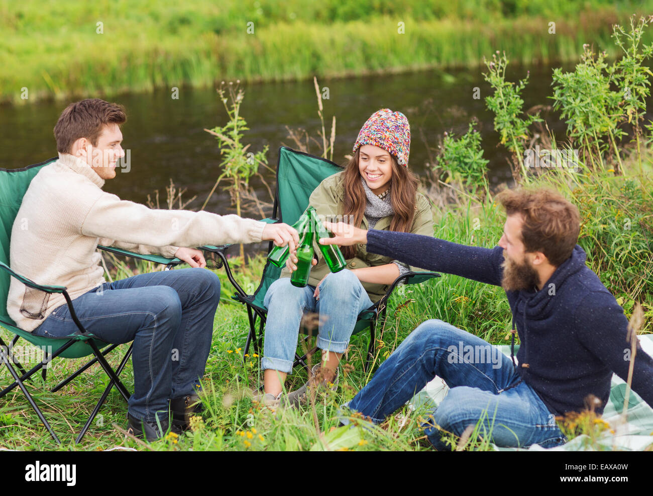 Groupe de touristes souriants de boire une bière en camping Banque D'Images
