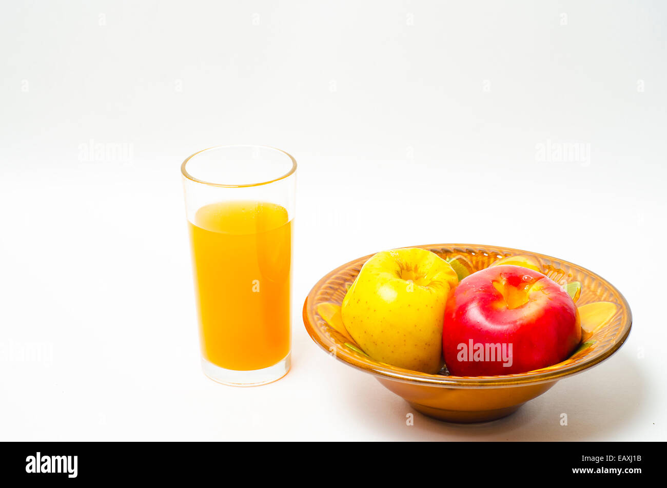 Pommes cuites dans un bol et le jus dans un verre, sur un fond blanc Banque D'Images