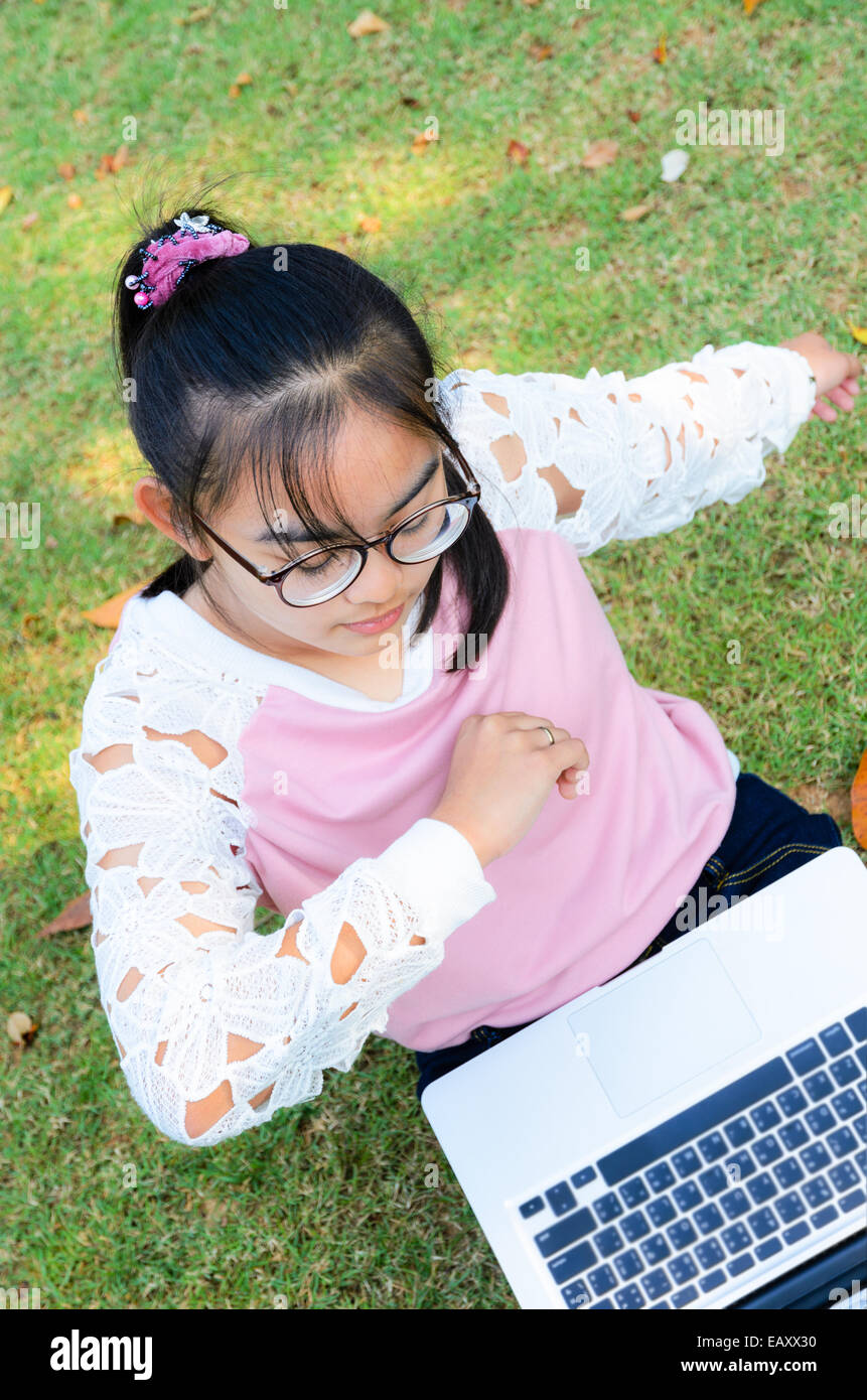 Jolie fille est heureux avec un ordinateur portable sur l'herbe dans le parc Banque D'Images