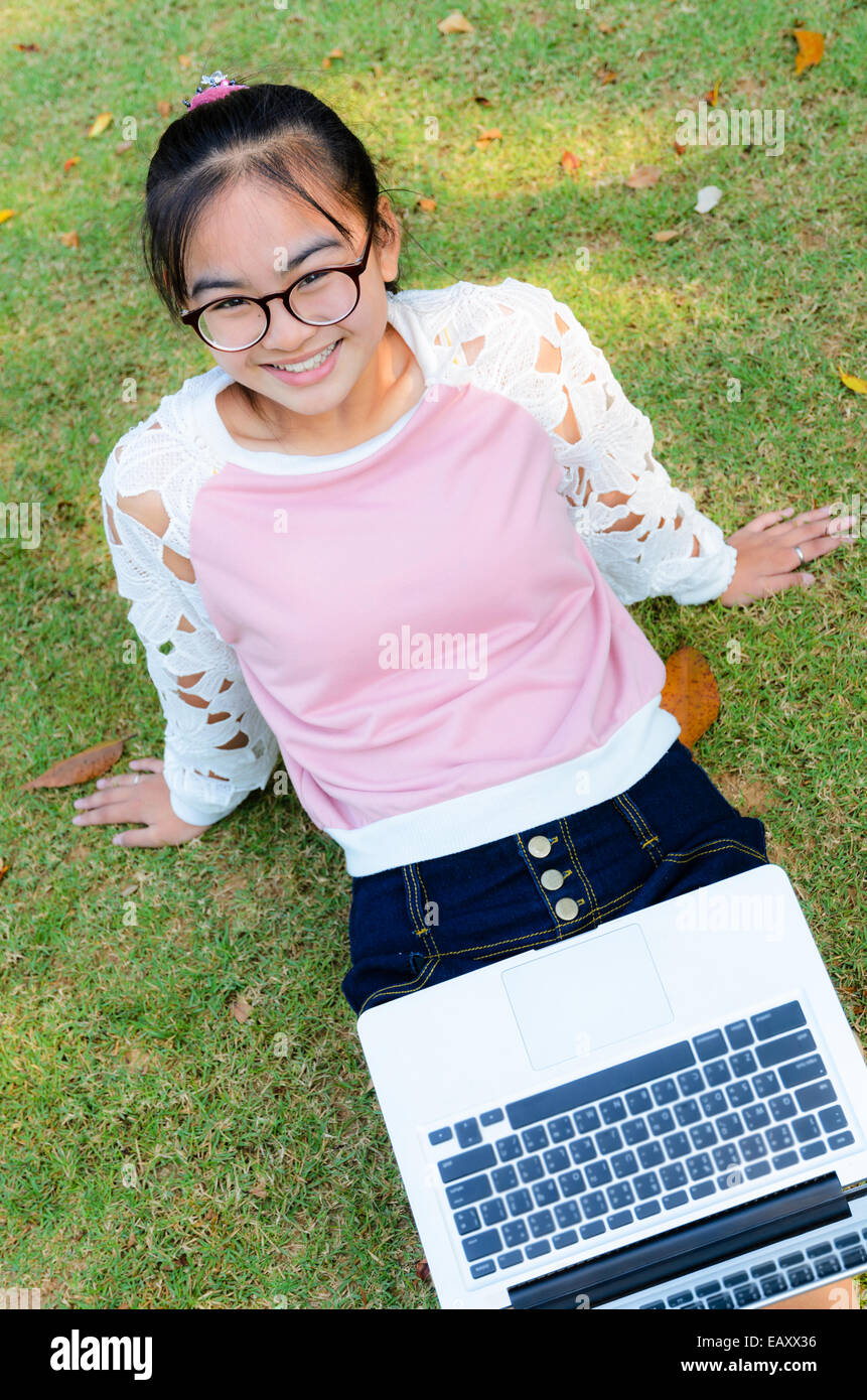 Jolie fille est heureux avec un ordinateur portable sur l'herbe dans le parc Banque D'Images