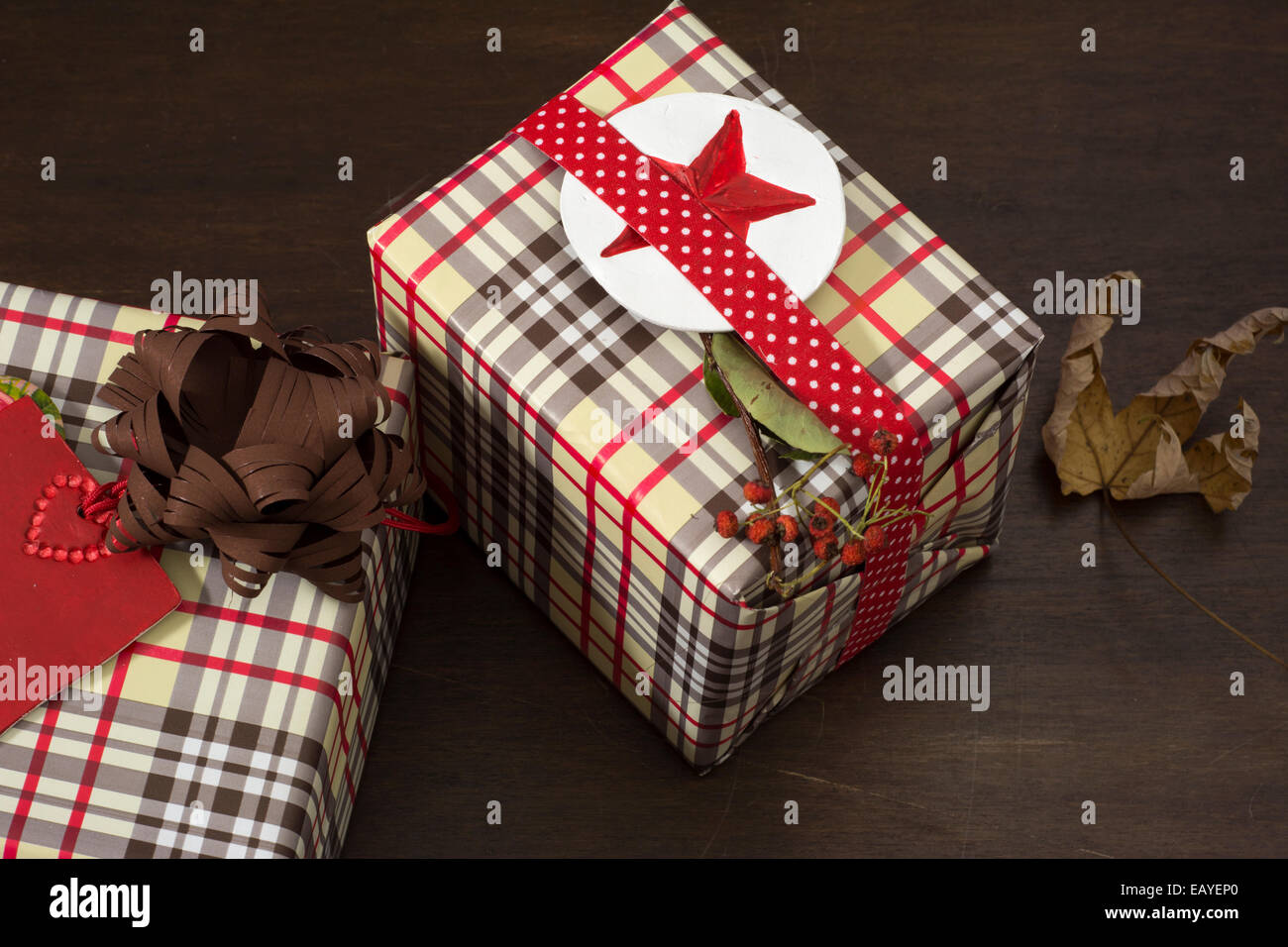 Présente enveloppés dans du papier à carreaux et ruban en pointillés avec l'étoile rouge sur fond de bois Banque D'Images