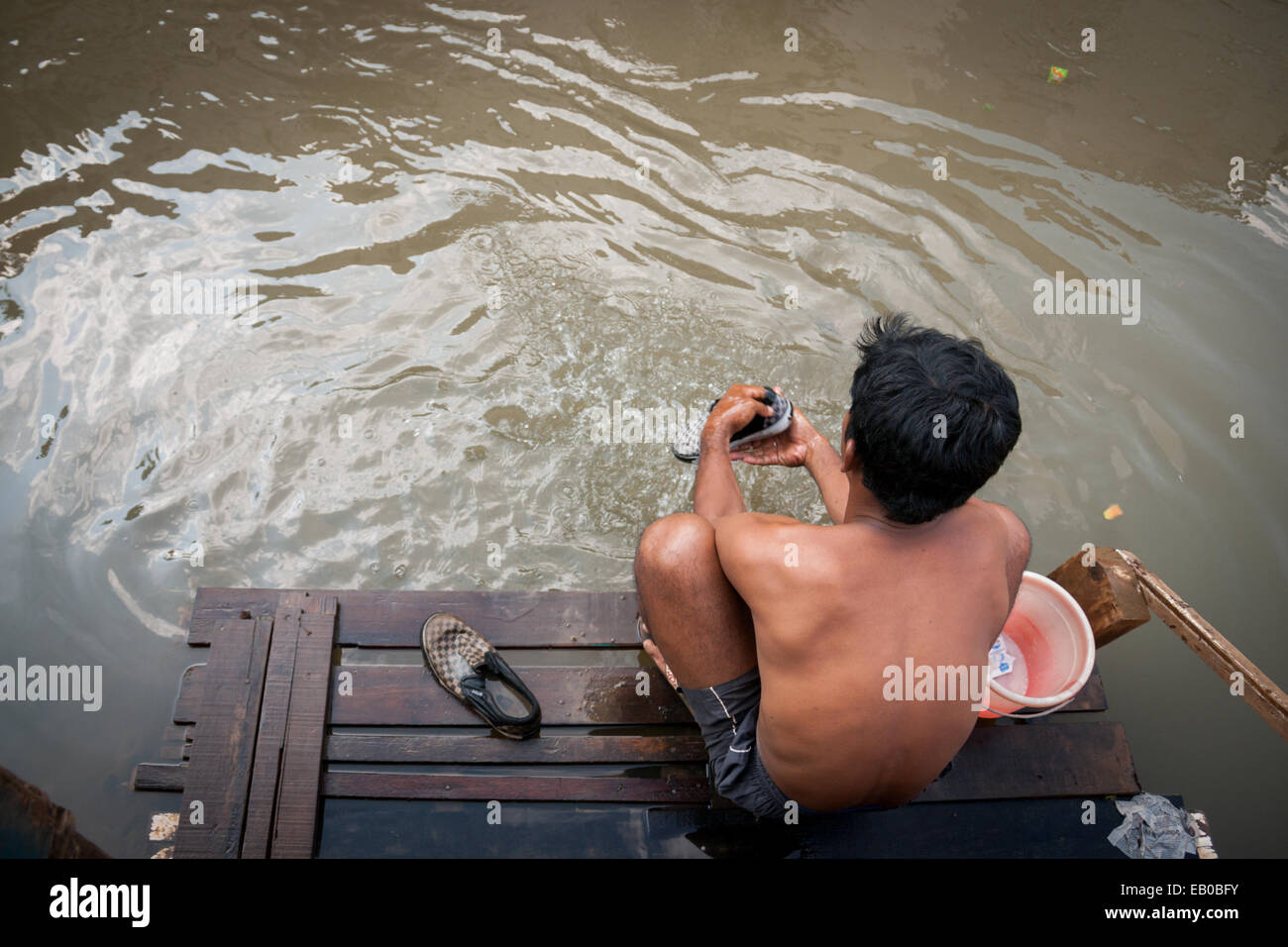 L'homme qui lave des vêtements sur la rivière Ciliwung, Jakarta. Ciliwung est déclaré comme l'un des plus forte pollution des rivières dans le monde. Banque D'Images