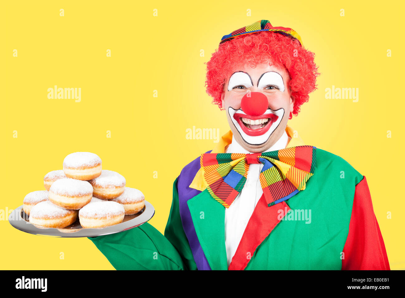 Clown avec crêpes de Berlin sur fond jaune Banque D'Images