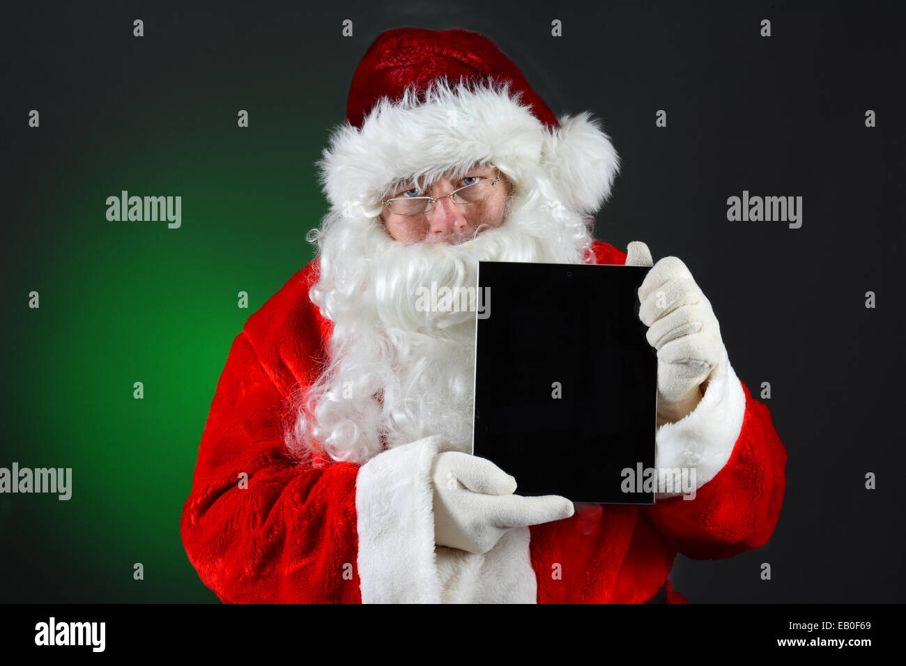 Santa Claus holding a tablet computer avec son écran vide face au spectateur en position verticale. Image horizontale sur une lig Banque D'Images