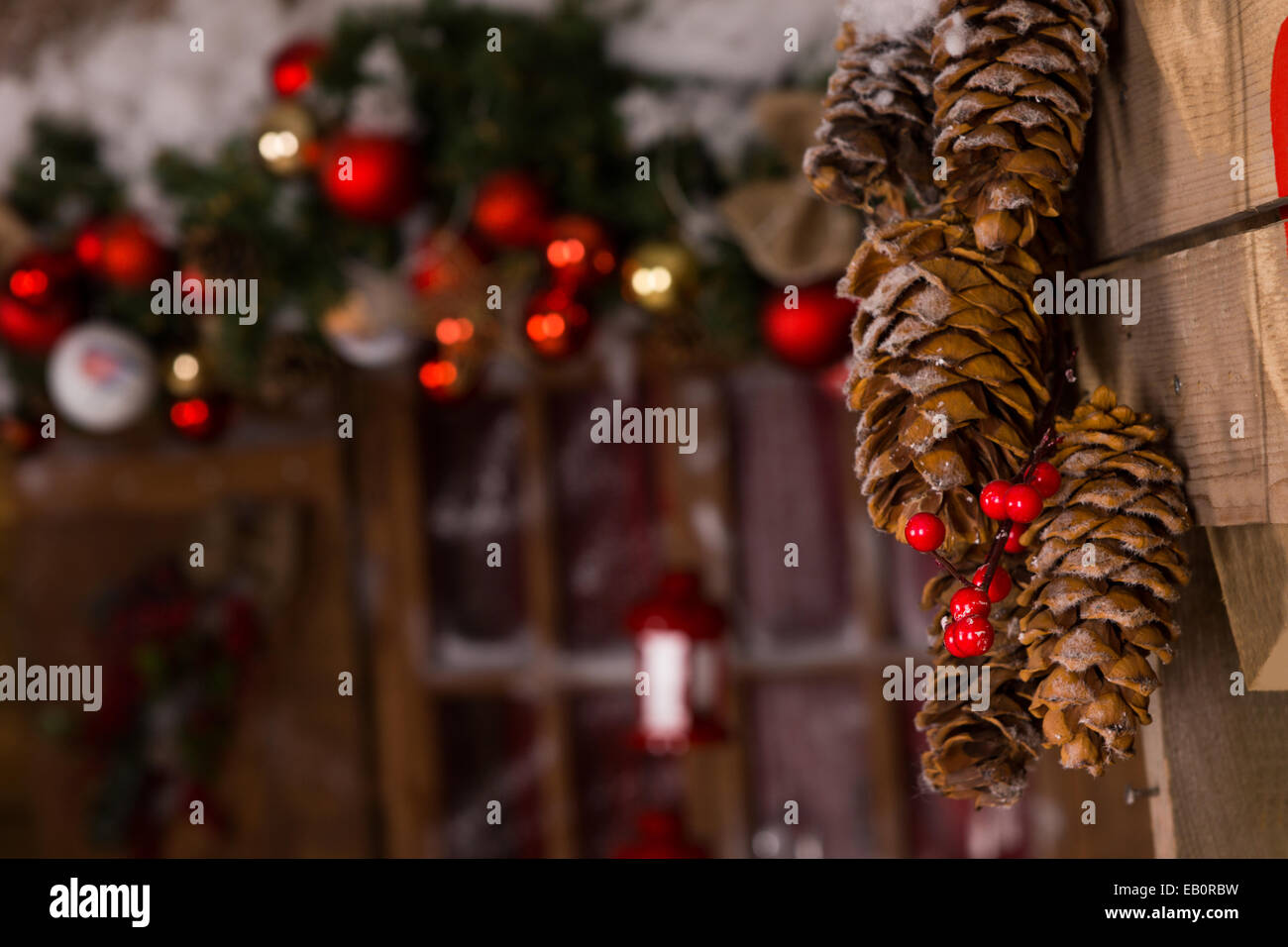 Cône de pin brun macro avec décors de Noël de Cerise rouge accroché sur un mur en bois à l'intérieur de la maison. Banque D'Images