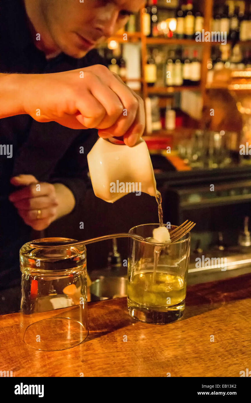 Un bartender pouring absinthe sur un morceau de sucre avant il allume le feu. Banque D'Images