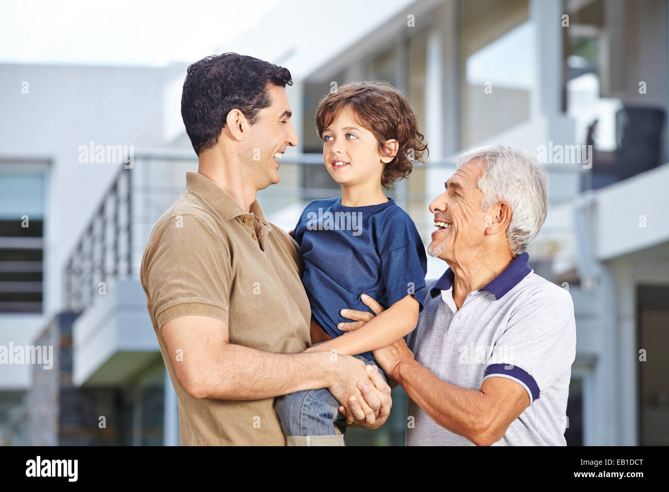 Heureux les hommes dans trois générations d'une famille devant une maison Banque D'Images