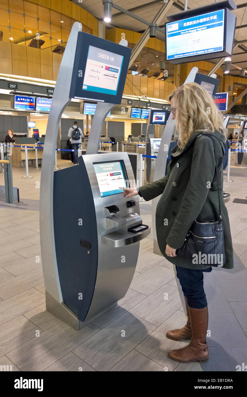 Femme à l'aide de l'une des bornes d'enregistrement de la compagnie aérienne à l'Aéroport International de Vancouver (YVR). Banque D'Images