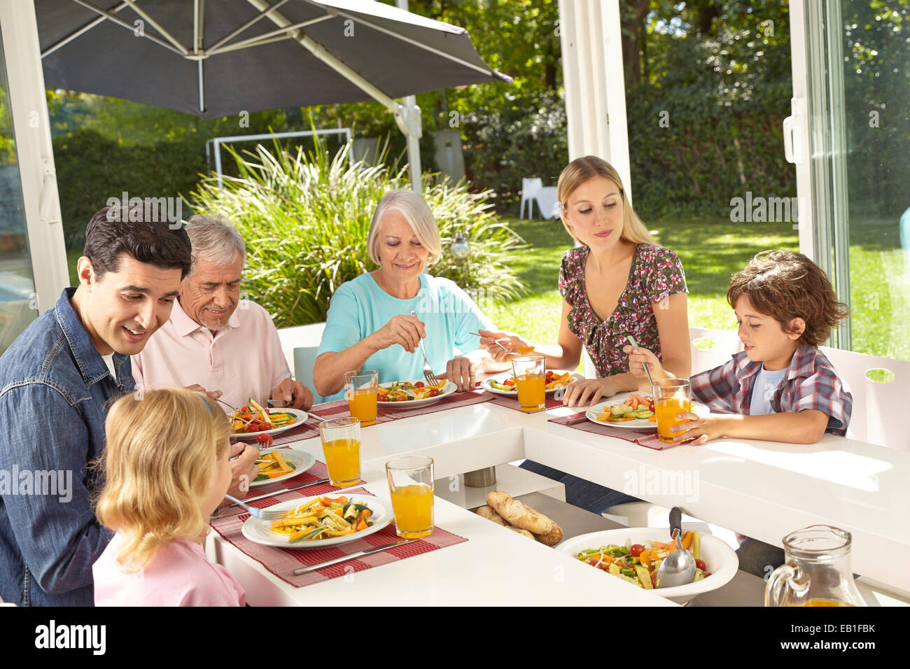 Famille heureuse dans trois générations de manger ensemble à midi en été Banque D'Images