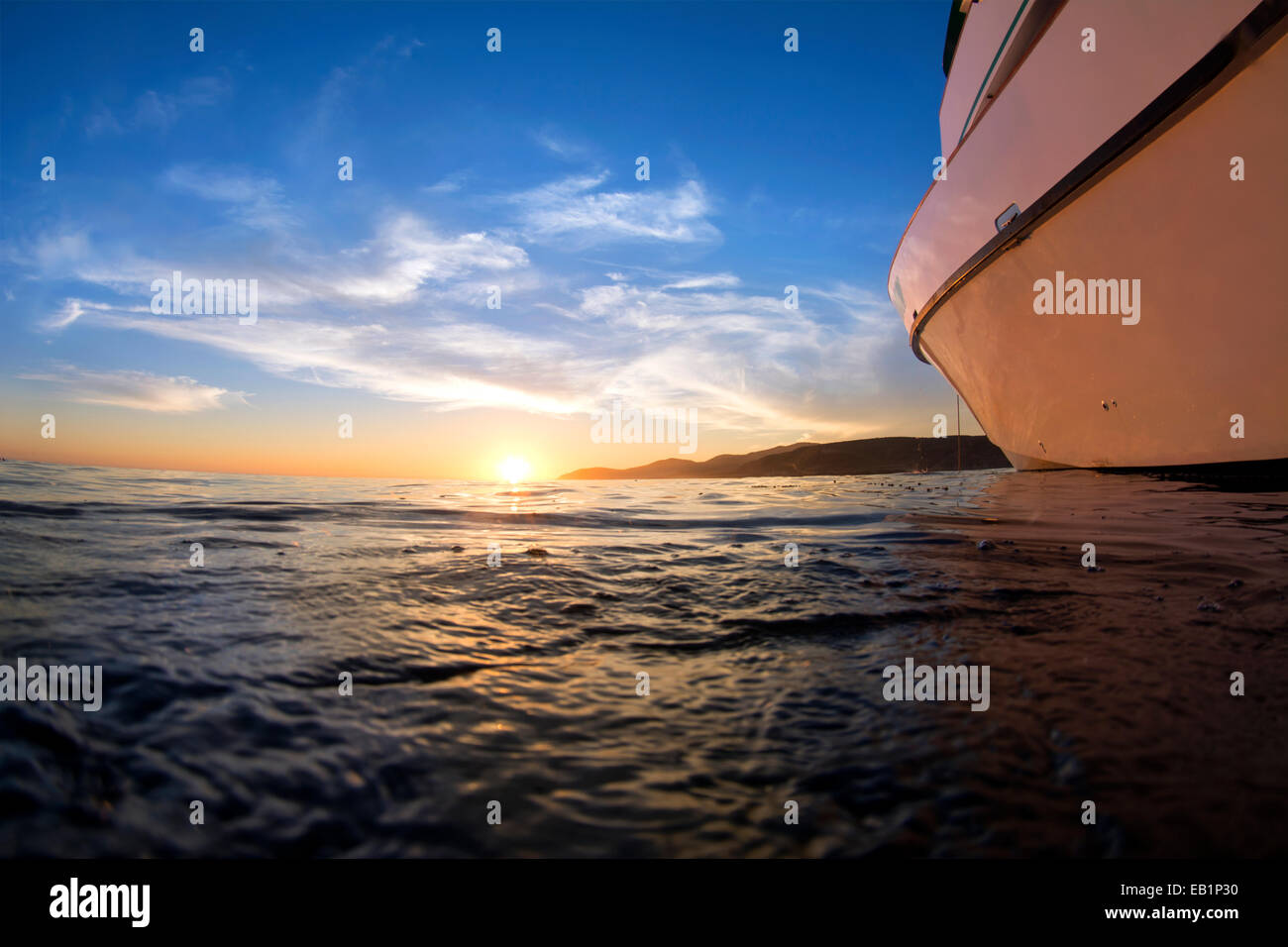 Vue d'un coucher de soleil depuis la surface de l'océan montre un bateau face à la magnifique nocturne horizon assure. Banque D'Images
