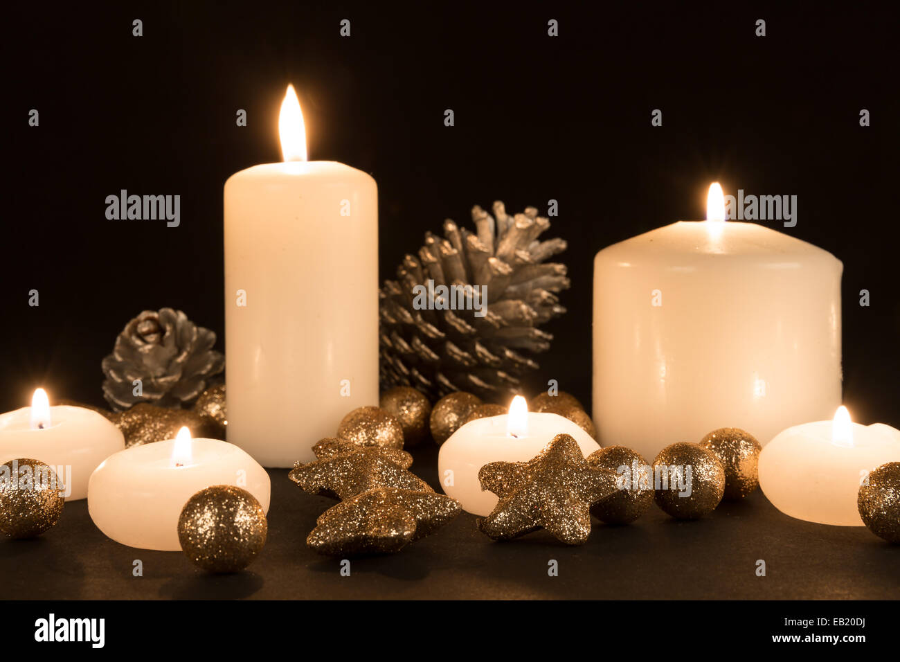 Brûler des bougies avec des pommes de pin et doré étoile à fond noir Banque D'Images