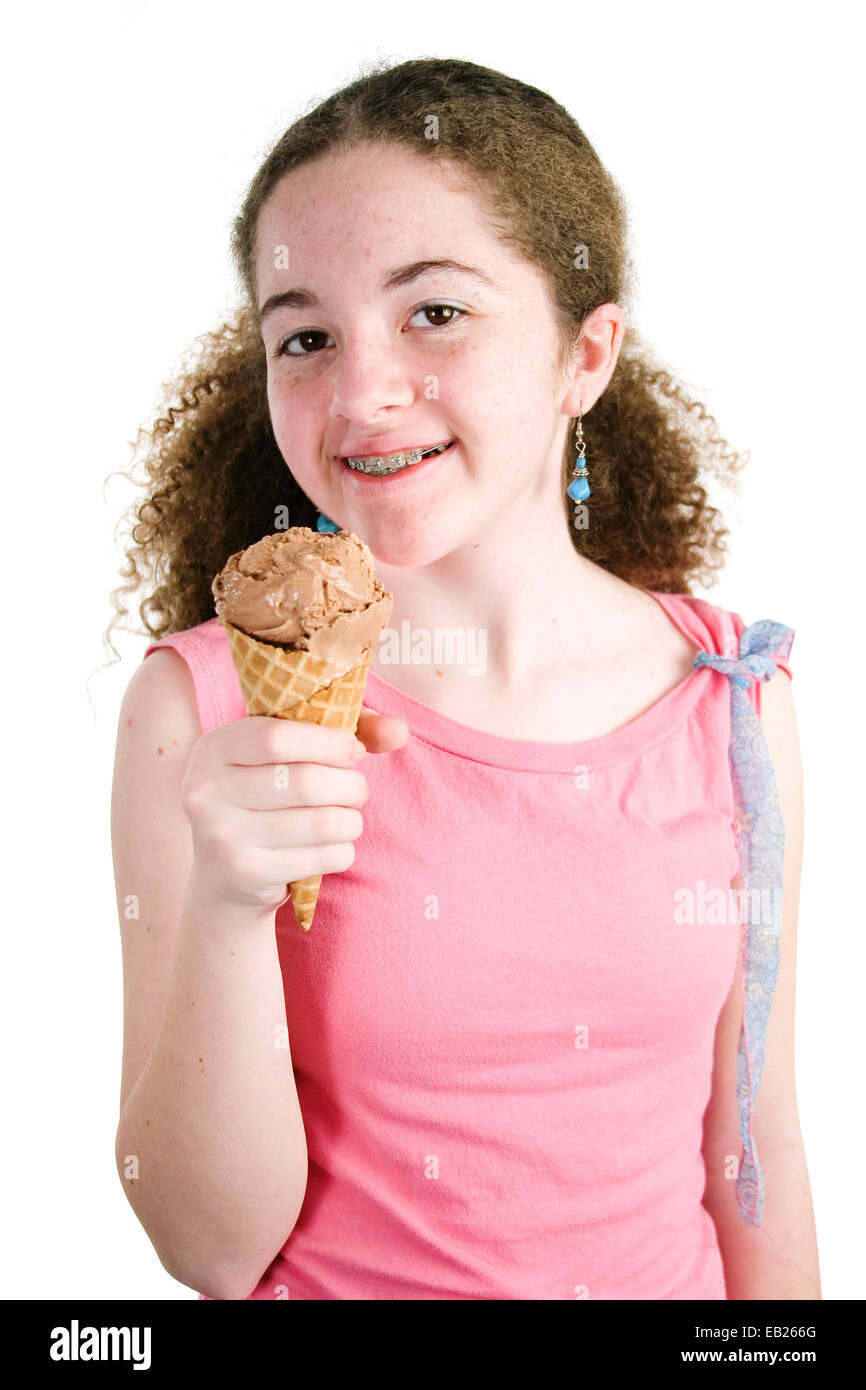 Cute young girl holding latina un cornet de crème glacée au chocolat et souriant à bretelles sur ses dents. Isolé sur blanc. Banque D'Images