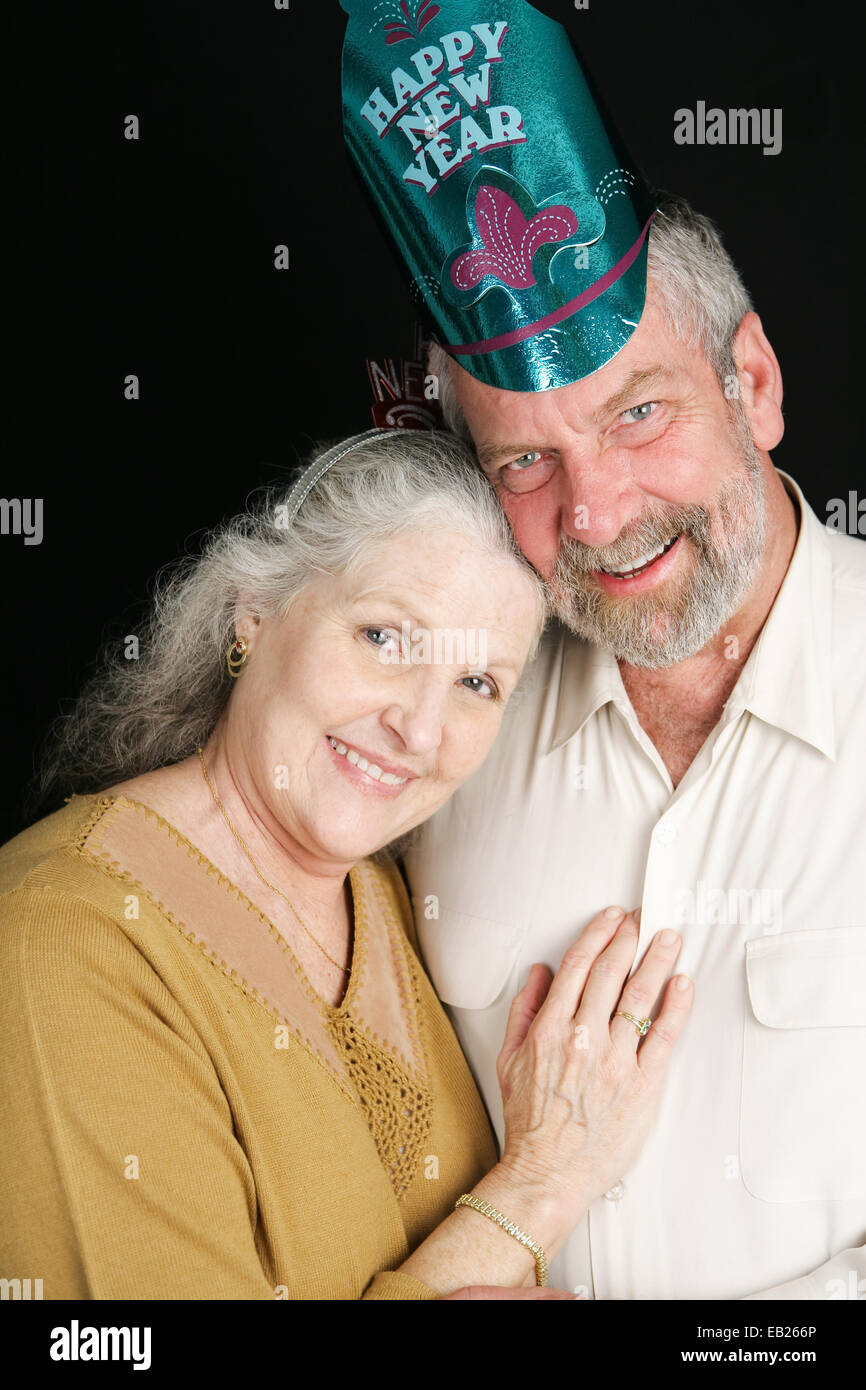 Beau couple dans la soixantaine qui pose pour un portrait romantique le soir du Nouvel An. Fond noir. Banque D'Images