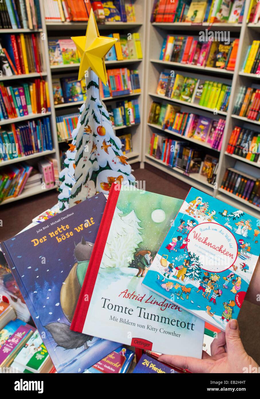 Francfort-sur-Oder, Allemagne. 24 Nov, 2014. ILLUSTRATION - une personne de ventes peut contenir trois nouveaux livres pour enfants pour Noël, 'Der nette boese Wolf' par Michael Derullieux de Belgique, Astrid Lindgren's "Tomte" Tummetott nouveau illustré par Kitty Crowther et un livre d'objets cachés colorés par Catharina Westphal 'Rund um die Welt ist Weihnachten' dans une librairie à Francfort-sur-Oder, Allemagne, 24 novembre 2014. Beaucoup de nouveaux livres pour enfants sont orientés en fonction de la saison de Noël. Photo : PATRICK PLEUL/dpa/Alamy Live News Banque D'Images