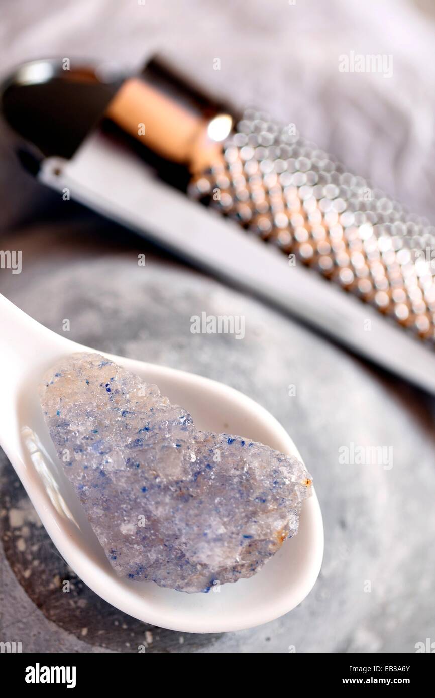 Cristal de Sel gemme en cuillère en porcelaine avec grater en arrière-plan Banque D'Images
