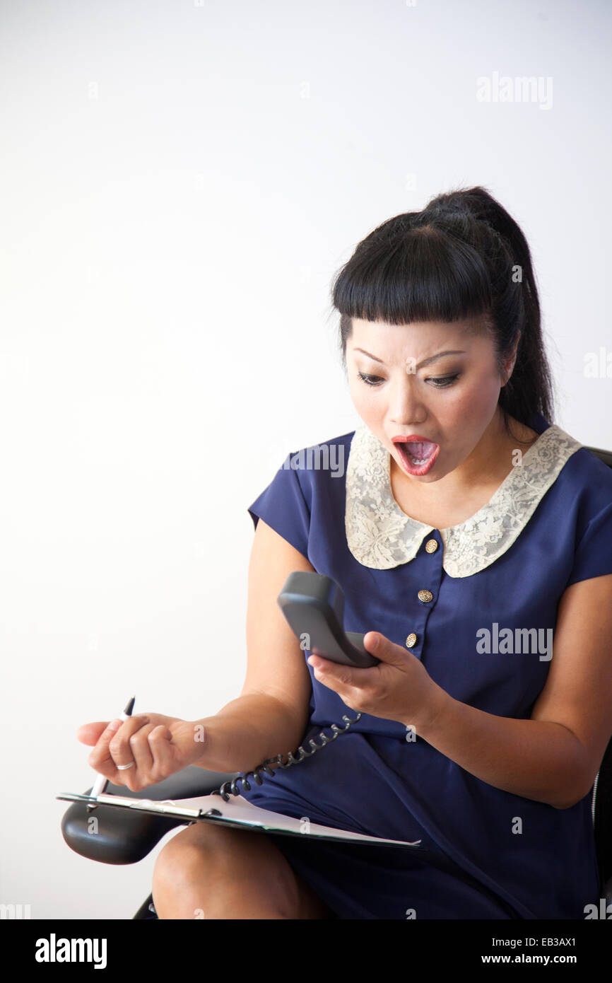 Téléphone fixe à l'aide d'une femme surprise Banque D'Images