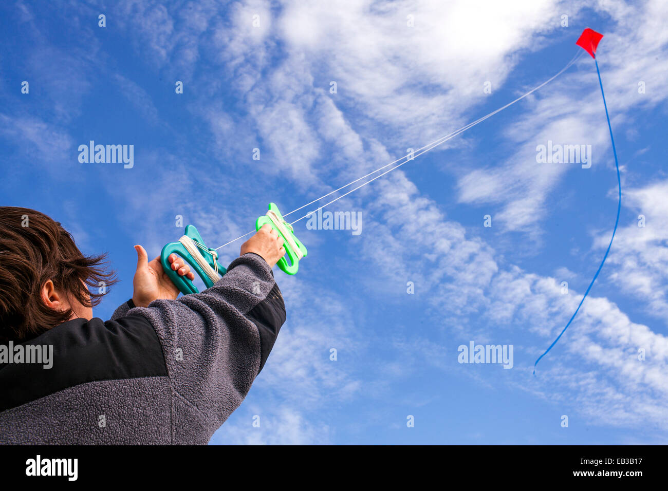 Low angle view of Caucasian man flying kite dans le ciel bleu Banque D'Images