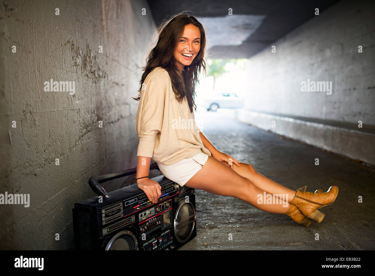 Caucasian woman sitting sur boom box in tunnel Banque D'Images