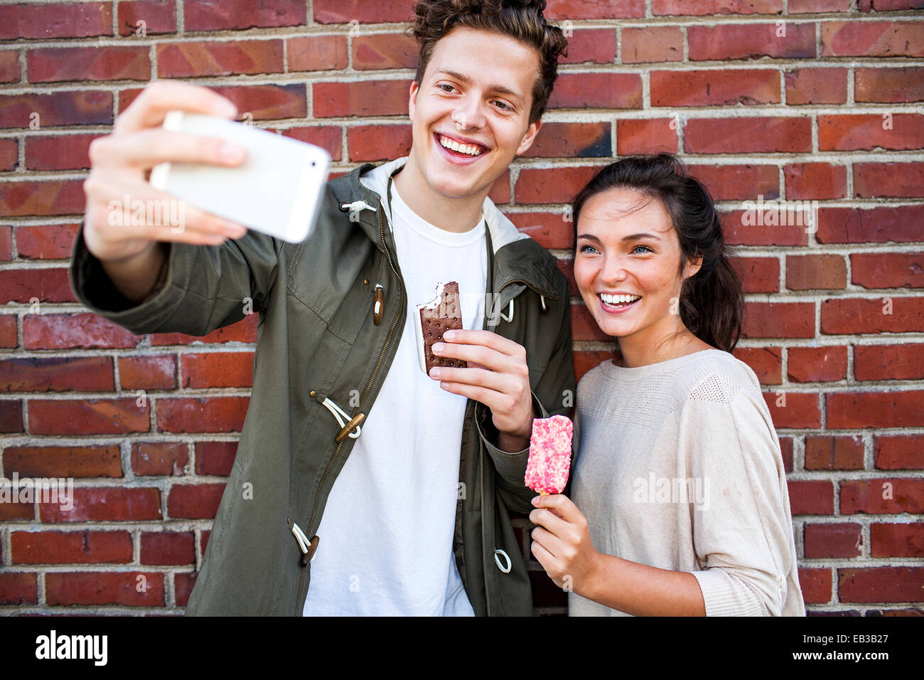 Couple en tenant près de selfies mur de brique rouge Banque D'Images