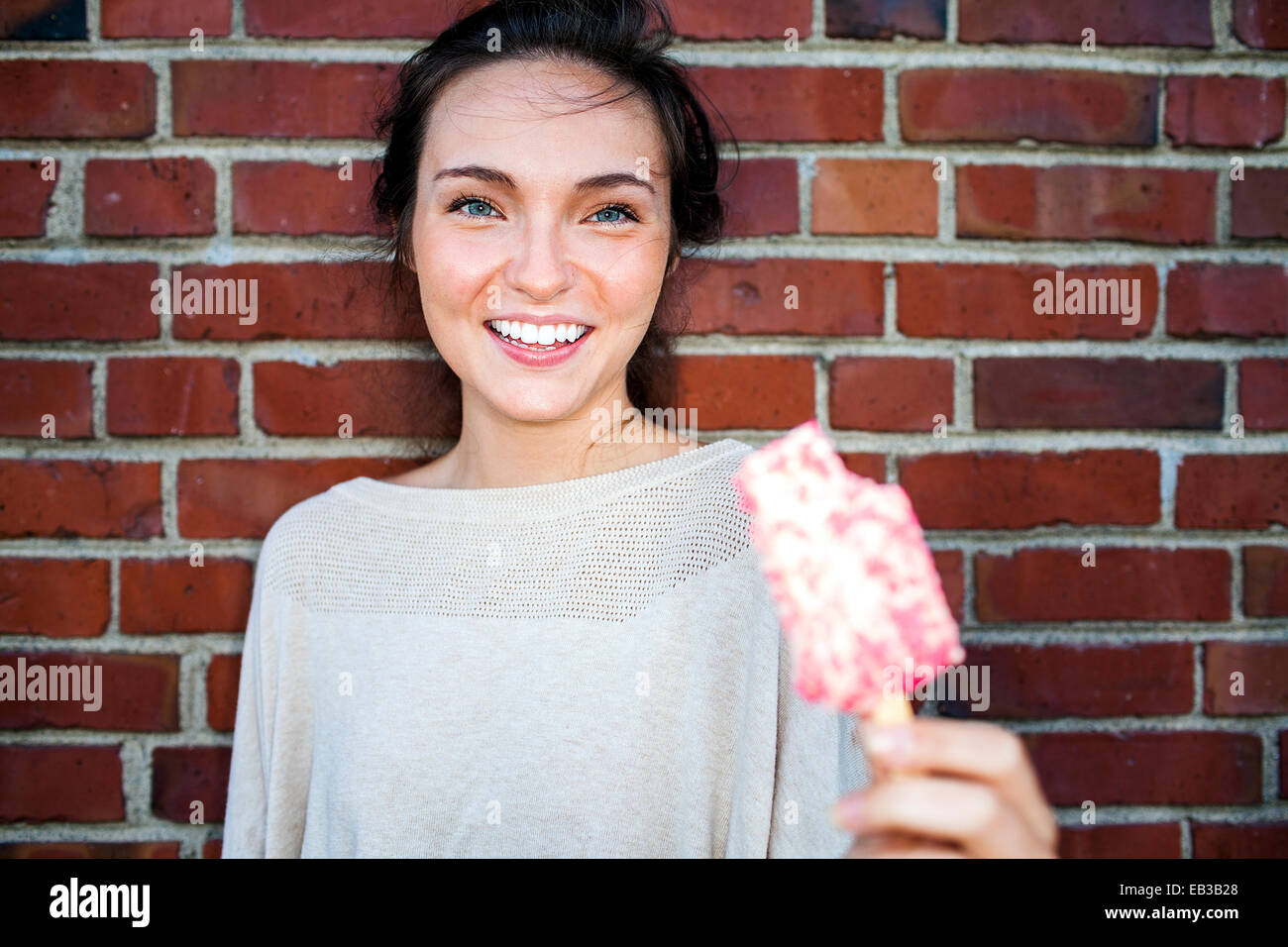 Young woman eating ice cream près de red brick wall Banque D'Images