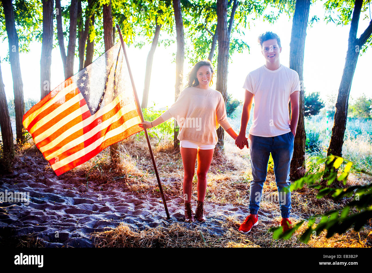 Young couple holding American flag in park Banque D'Images