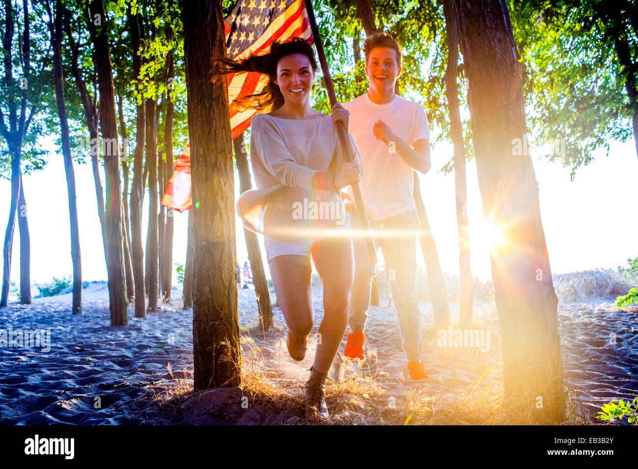 Caucasian couple exerçant son drapeau américain dans les arbres on beach Banque D'Images