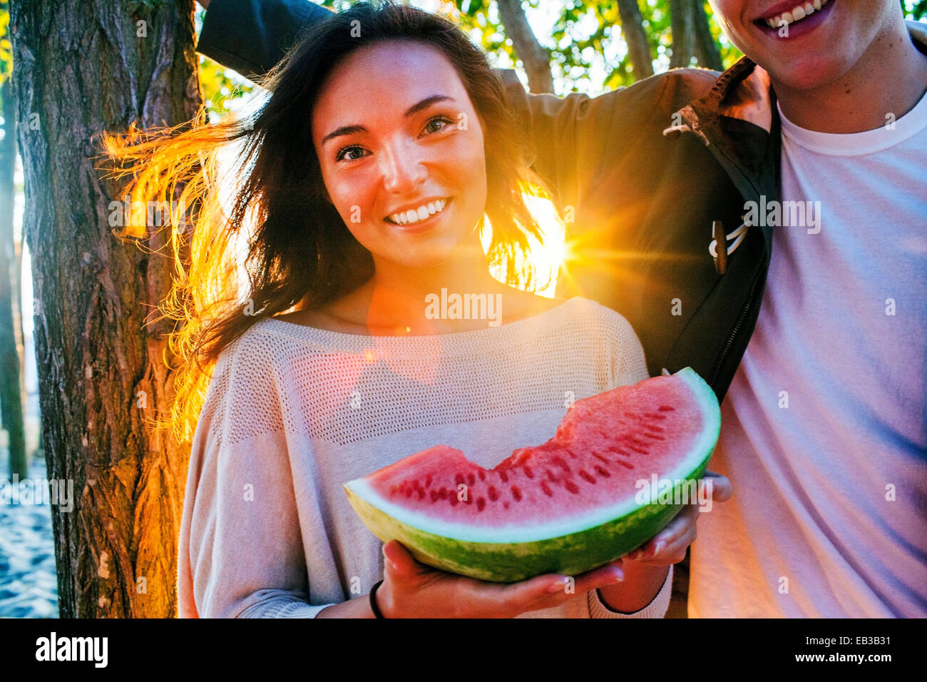 Caucasian couple eating watermelon at sunset Banque D'Images