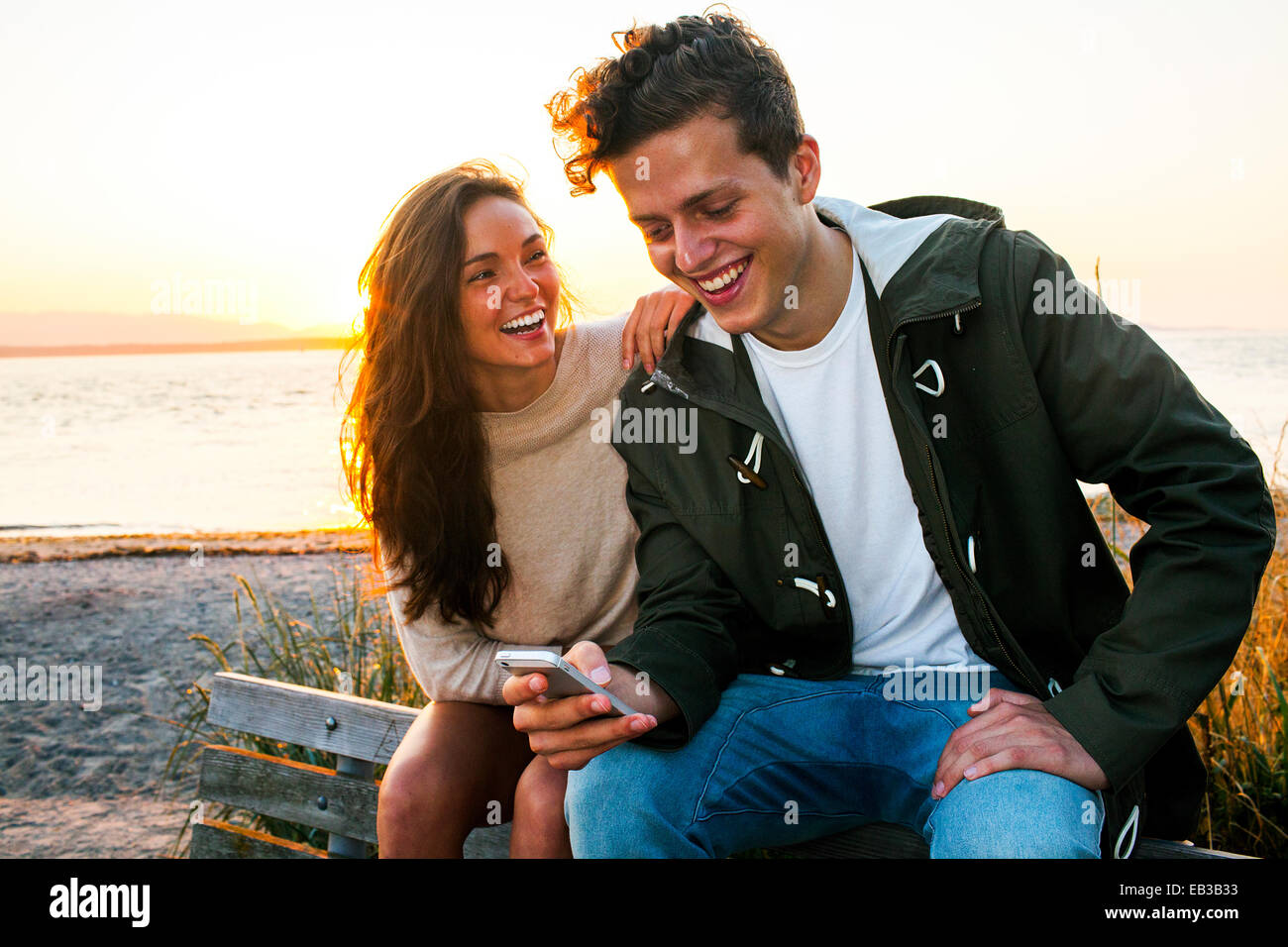 Caucasian couple using cell phone on beach Banque D'Images