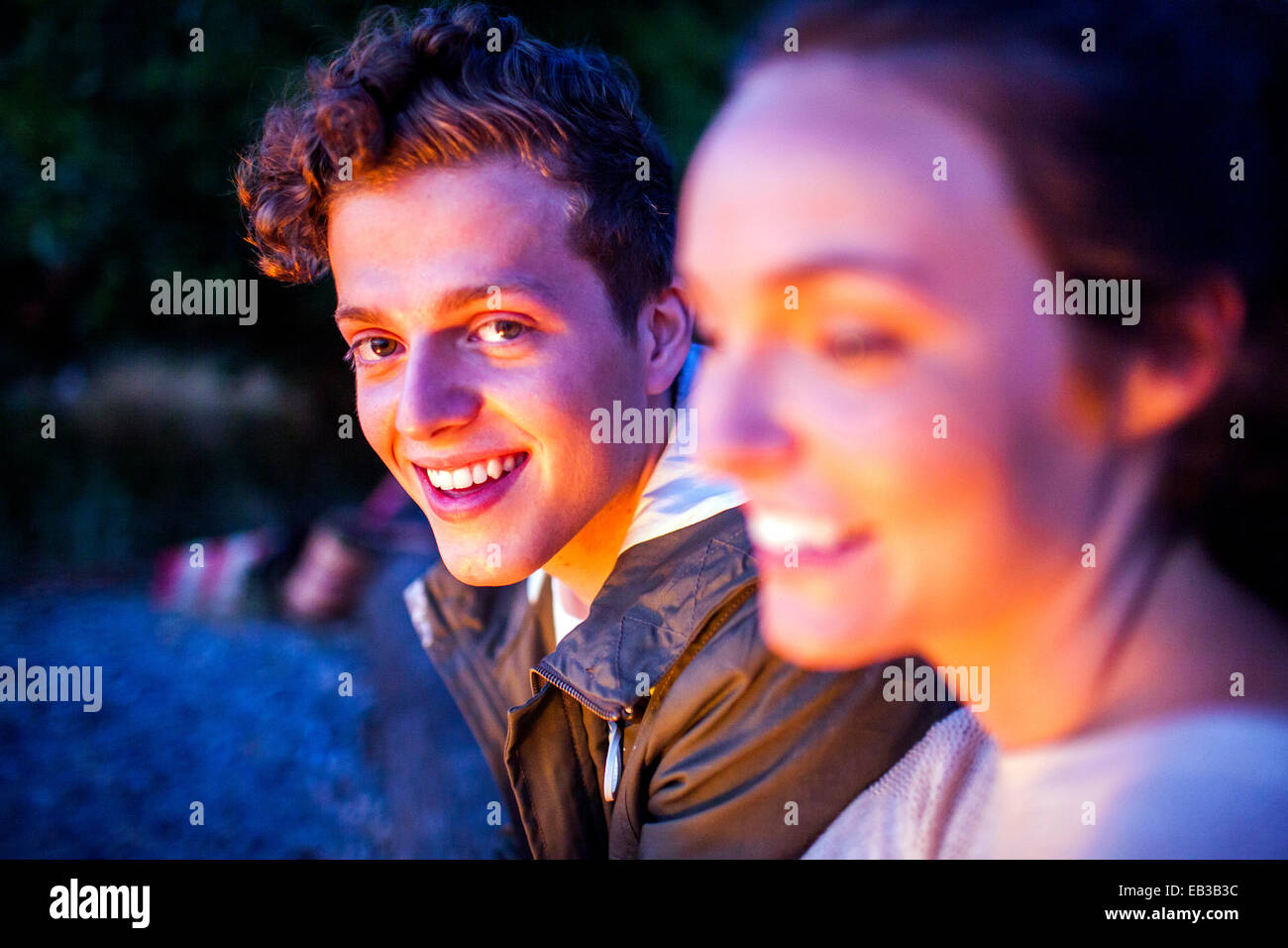Caucasian couple relaxing together on beach at night Banque D'Images