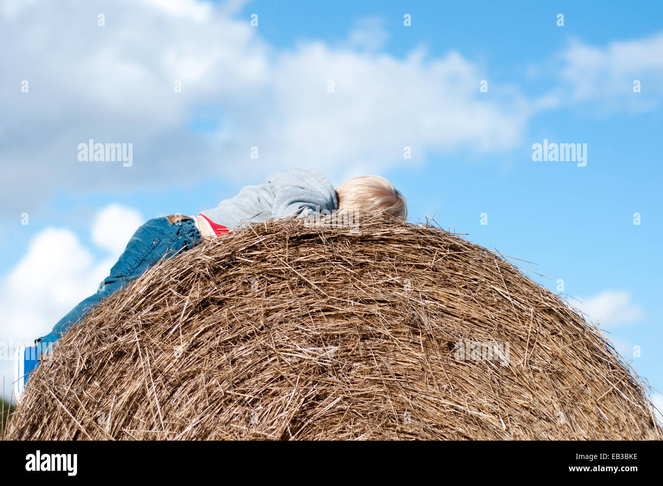 Boy lying on hay bale Banque D'Images