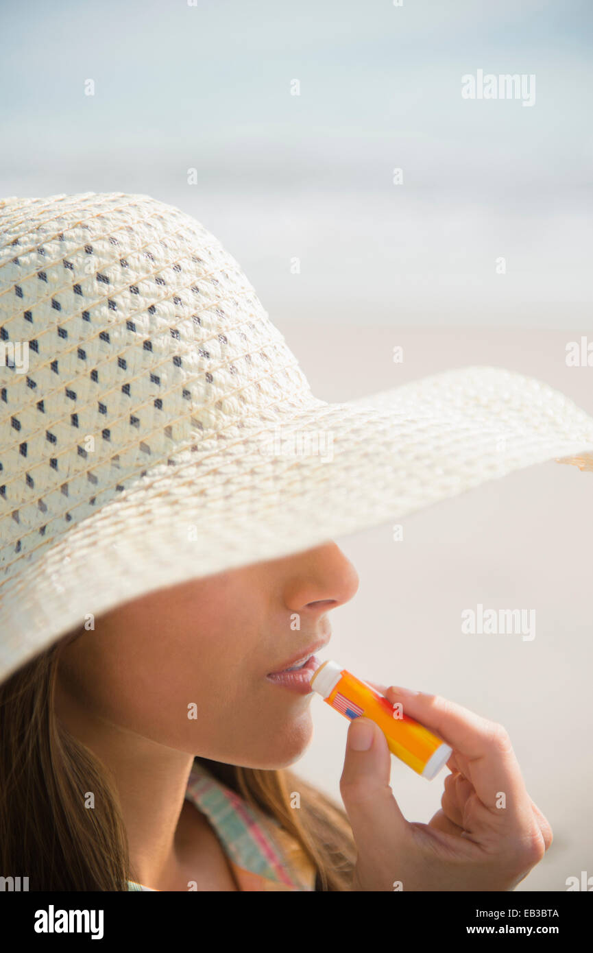 Caucasian woman appliquez un écran solaire pour les lèvres at beach Banque D'Images