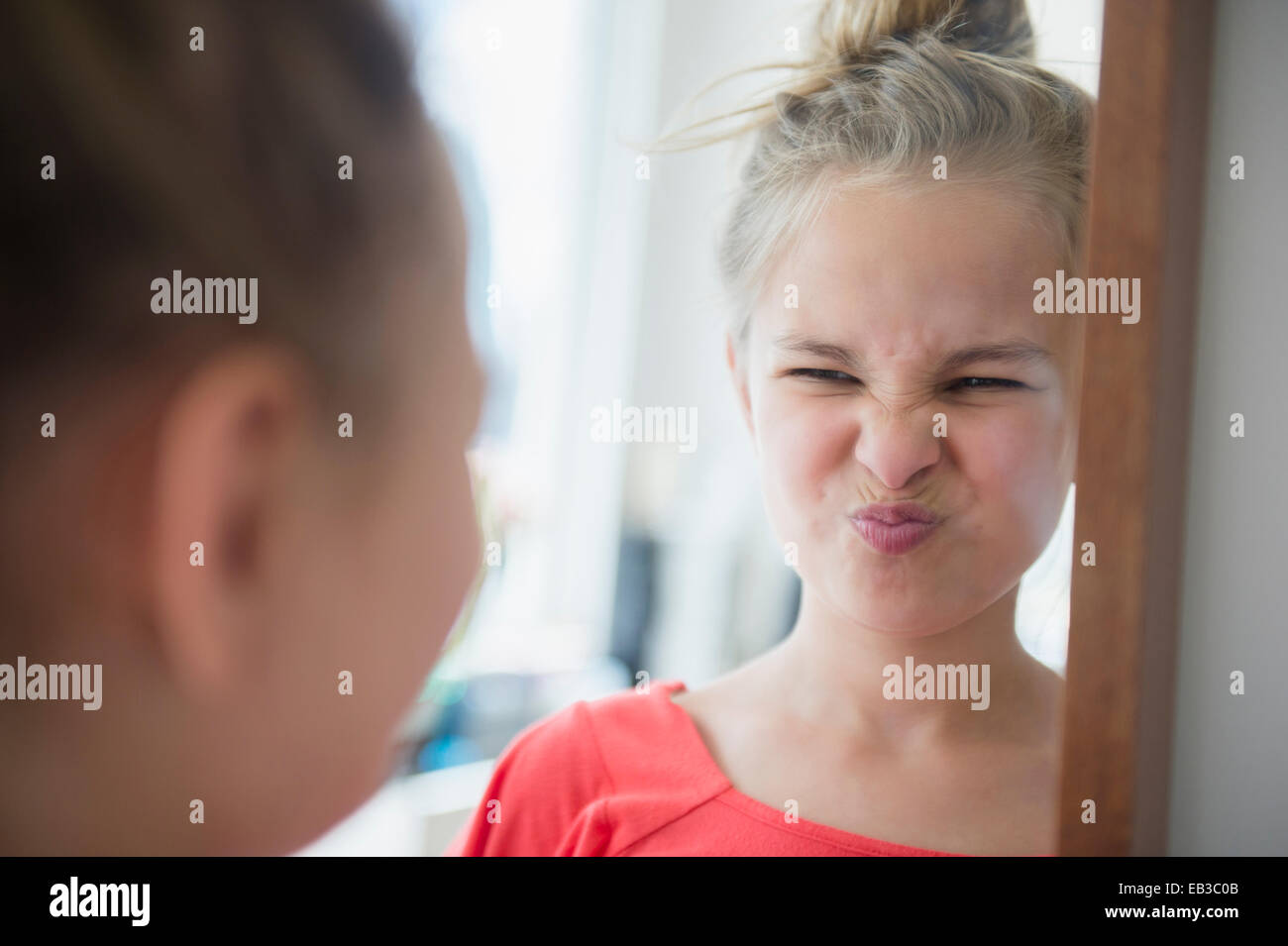 Caucasian girl scrunching jusqu'son visage dans le miroir Banque D'Images