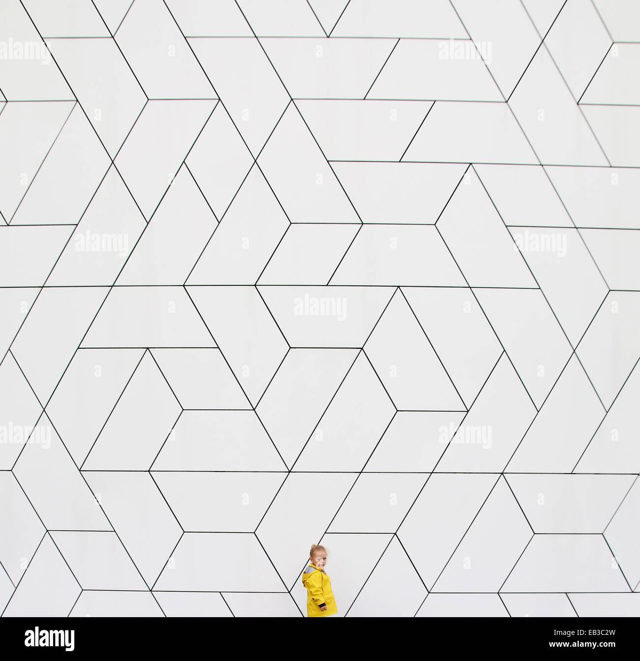 Fille dans un imperméable jaune debout près d'un mur Banque D'Images