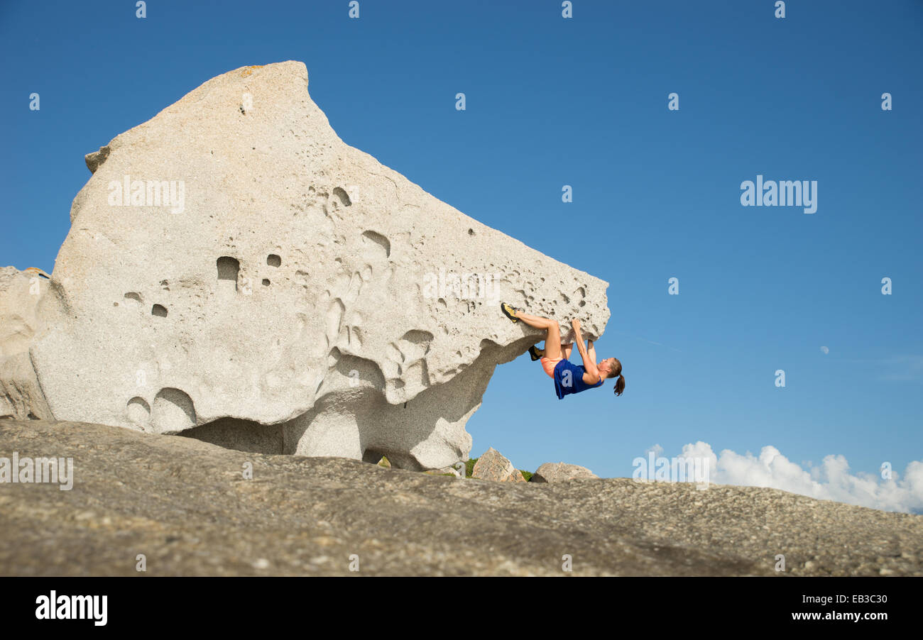 Vue latérale d'une femme grimpant un grand rocher, Corse, France Banque D'Images